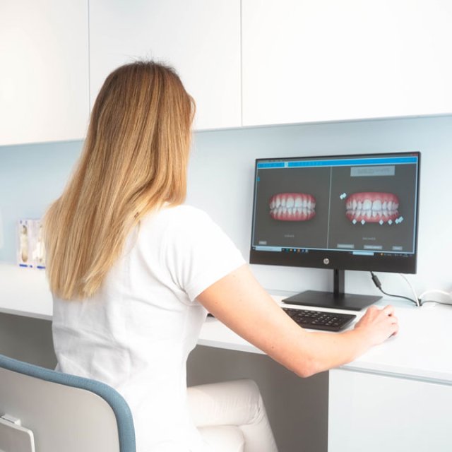 Staff member at a screen showing a 3D simulation of the teeth
