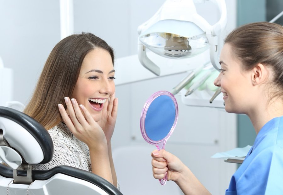 Patient in the treatment chair delighted with her smile in the mirror