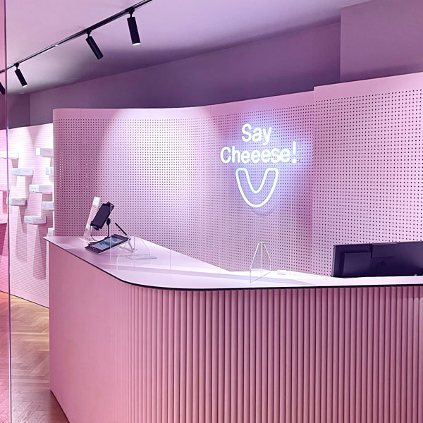 Pink reception desk of the practice with a SayCheeese neon sign